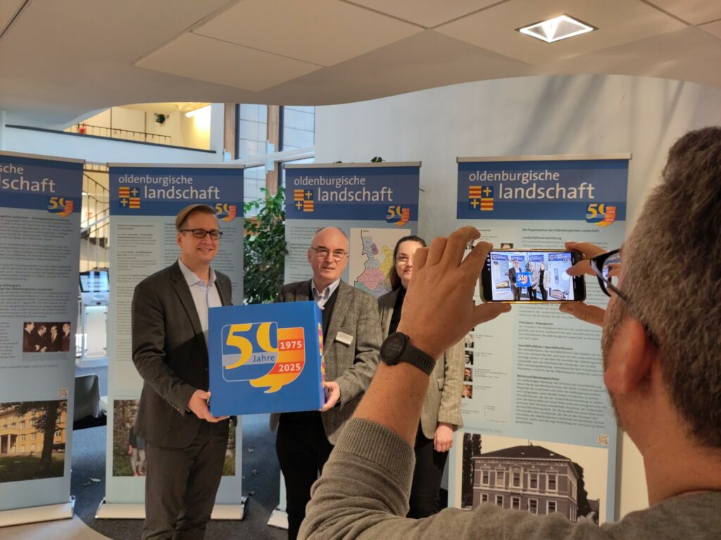 Eröffnung der Wanderausstellung zum Landschaftsjubiläum auf ihrer Station im Landkreis Wesermarsch am 4.2.2026 im Kreishaus Brake.  
vlnr.: Landrat Stephan Siefken, st. Geschäftsführer Oldenburgische Landschaft Dr. Jörgen Welp, Projektkoordinatorin Merle Bülter. Fotos SCS/Oldenburgische Landschaft 
